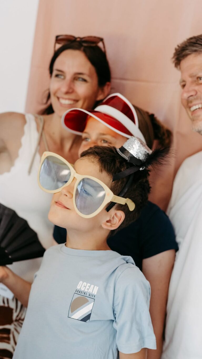Ein Kind mit übergroßer Sonnenbrille beim Sommerfest zum einjährigen Bestehen, dahinter Erwachsene