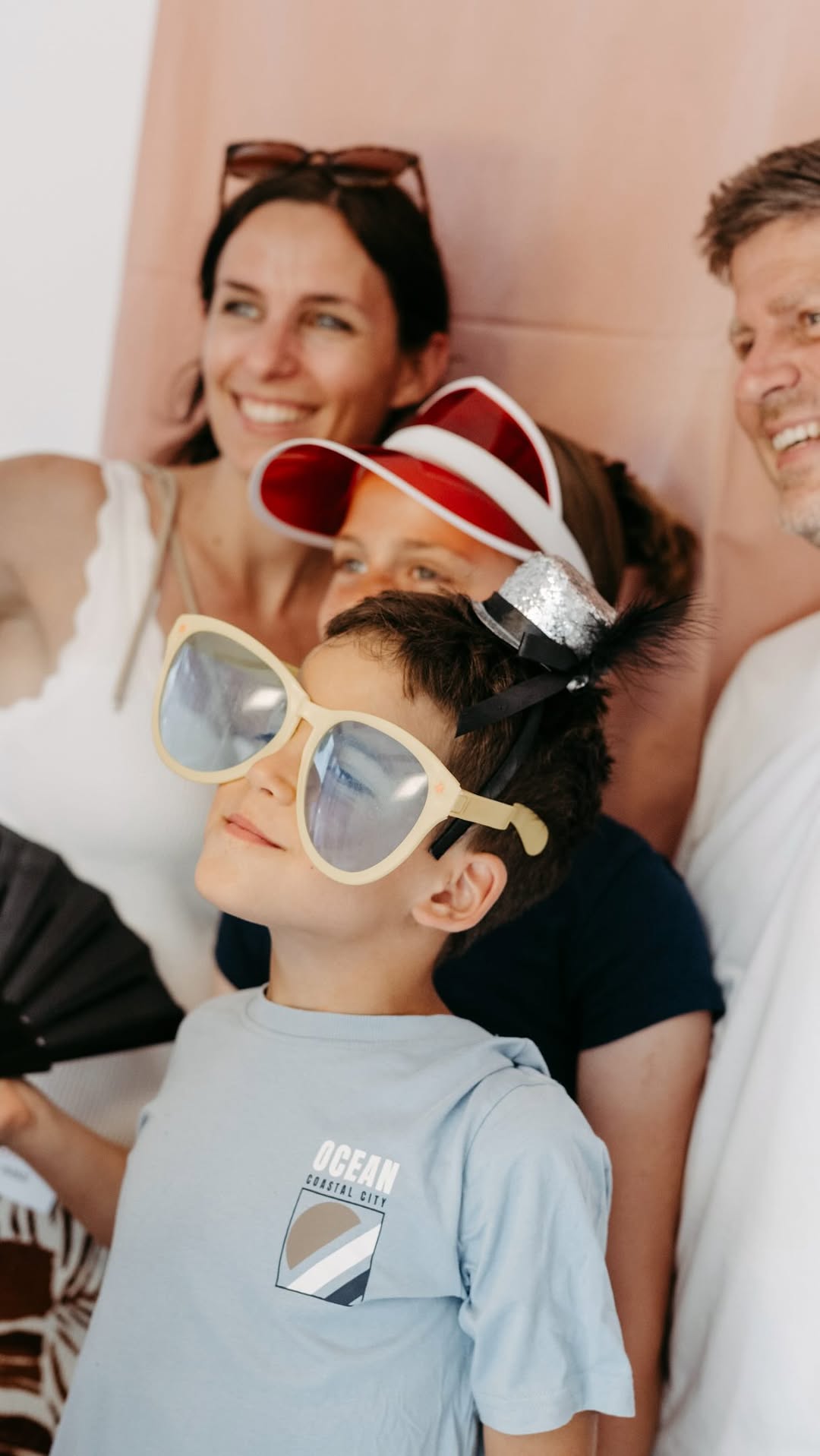 Ein Kind mit übergroßer Sonnenbrille beim Sommerfest zum einjährigen Bestehen, dahinter Erwachsene